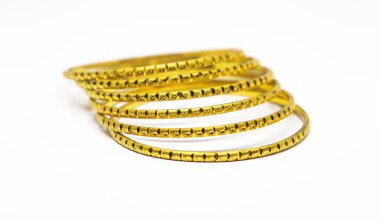 Üst üste dizilmiş altın bilezikler, ayrıntılı desenli tasarımlar, lüks bir his için temiz beyaz bir arkaplan üzerine kurulmuş..