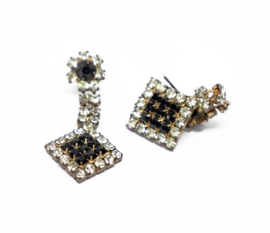 Asılan bir tasarımı olan kare şeklinde küpeler, el değmemiş beyaz bir zemin üzerine yerleştirilmiş pırıltılı elmas elmaslarla güçlendirilmiş..