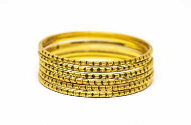 Yakın plan, dekoratif süslemeleri vurgulayan, temiz beyaz bir arkaplanda izole edilmiş, karmaşık bir şekilde tasarlanmış altın bilezikler yığını sunar..