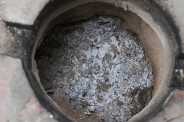 Yuvarlak tuğlalı fırının içi gri ve beyaz kül kalıntılarıyla dolu. Küller fırının içine saçılmış..