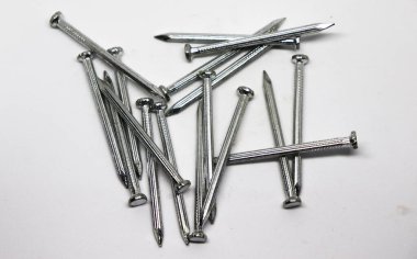 Bir yığın parlak metal çivi beyaz bir yüzey üzerinde rastgele gruplandırılır. Bağlayıcılar inşaat malzemelerinde detay gösteriyor.