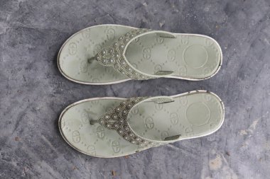 Tepeden çekimde gri desenli yüzeyde iki açık yeşil sandalet ve değerli süslemeler var. Moda ve yaz ayakkabıları..