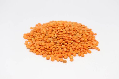 Yakından çekilen, bir yığın kurumuş kırmızı mercimek, pürüzsüz, yuvarlak baklaklar, sert beyaz arka plana karşı dokulu bir tümsek oluşturur..