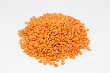 Bu yakın çekim bir yığın ham, canlı kırmızı mercimeği temiz, beyaz arka planda yakalıyor. Mercimek küçük ve yuvarlaktır, desenli bir yüzey yaratır..