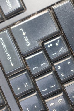 Bu fotoğraf Enter, Backspace, Sil, artı / eksi gibi biraz kirli bir bilgisayar klavyesinin yakın plan görüntüsünü ortaya çıkarır. Anahtarlar İngilizce ve diğer alfabeleri içeriyor.