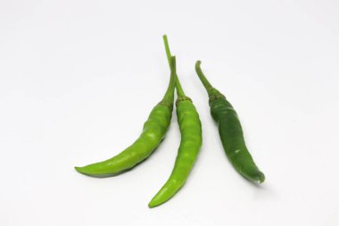 Beyaz arka planda, bağlı sapları olan üç taze yeşil biber gözlemlenir, biber, sade bir tuvalde görsel olarak çekici bir yaşam düzenindedir..