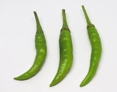 Parlak beyaz arka planda üç yeşil biber standı; canlı renkleri ve yakın düzenlemeleri mutfak temaları için basit, etkili bir resim oluşturur.