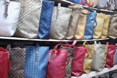 Parlak deri çantalardan oluşan çeşitli bir dizi perakende bir rafta, benzersiz dokularını ve metal aksanlarını sergileyerek müşteriler için hazırlandı..
