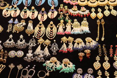 Altın, gümüş ve mücevher içeren bir dizi küpe, etnik mücevherlerin karmaşıklığını gözler önüne seriyor. Her çift, siyah bir arkaplana karşı kurulmuş zanaat, renk ve tarzın altını çizer.