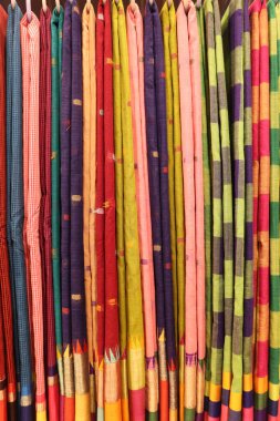 Yakından bakıldığında, geleneksel sanatsal becerilerin altını çizerek, karmaşık detaylar, belirgin desenler ve parlak renkler içeren çeşitli pamuk sariler sergileniyor..