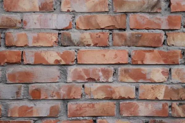 Eski bir tuğla duvarın desenini ve rengini çeken yakın plan çekim, yıpranmış kırmızı tuğlalar ve yüzey ayrıntıları ve inşaata odaklı gri havan topları.