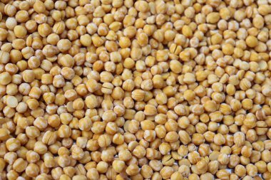 Kurumuş birçok bezelyenin yakın çekim görüntüsü çerçeveyi ışıkla ve yüzeydeki gölge nüanslarıyla dolduran yoğun bir şablon oluşturuyor..