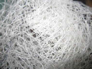 Soyut yakın plan, birbirine sıkıca bağlı iplikçiklerden oluşan karmaşık bir ağı gözler önüne seriyor. Beyaz iplik, arka plan için harika, büyüleyici ve büyüleyici bir doku yaratıyor..