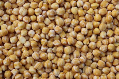 Görüntü yüksek bir açı sergiliyor. Yoğun ve dokulu bir desen oluşturan sayısız sarı bezelyeyi kapatıyor. Bezelyeler eşit dağıtıldı, çerçeveyi bu parlak sahnede dolduruyorlar..