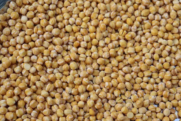 Yakın planda çok sayıda kuru, sarı bezelye var. Bu baklagiller kümelenmiş düzenleriyle görsel ilgi sağlayan pürüzsüz, küresel bir forma sahiptirler..