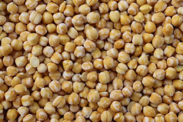 Görüntü yüksek bir açı sergiliyor. Yoğun ve dokulu bir desen oluşturan sayısız sarı bezelyeyi kapatıyor. Bezelyeler eşit dağıtıldı, çerçeveyi bu parlak sahnede dolduruyorlar..