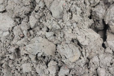 Gri toprak yığınının yakın görüntüsünde pürüzlü ve pürüzlü bir doku var. Sıkıştırılmış toprak, daha küçük parçalara ayrıldığını gösteriyor..