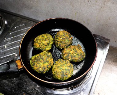 Yakın plan çekimde tavada ıspanaklı börek, siyah saplı fırında pişiyor. Bu, bu köfteleri ve onların detaylarını hazırlama sürecini yakalar..