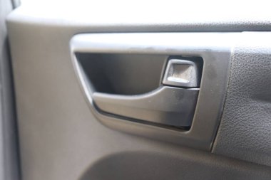 Detaylı olarak yakalanan siyah bir arabanın iç kapı kolu, gri desenli bir kapı paneliyle birlikte belirgin bir şekilde görülüyor. Odaklanma sıkı, gösterişli doku ve tasarım.