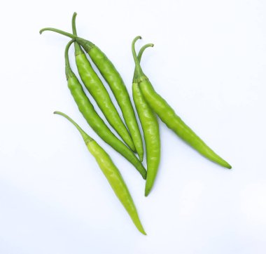 Bu resim, titiz beyaz bir arkaplana dikkatlice yerleştirilmiş canlı yeşil kırmızı biber koleksiyonunu gösteriyor. Kompozisyonda canlı renkleri ve dokuları vurgulanıyor..