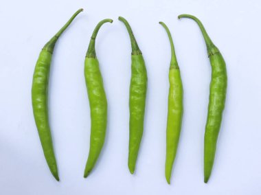 Yukarıdan aşağıya doğru çekilen beş taze yeşil biber beyaz bir arkaplanda dikkatlice düzenlenerek doğal şekillerini ve canlı renklerini gözler önüne seriyor.,