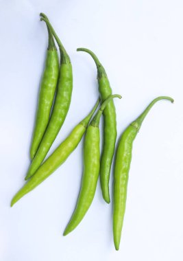 Yukarıdan aşağıya bakan bir görüntüde taze, açık yeşil kırmızı biberler sergileniyor. Beyaz arka planda sergileniyor. Canlı renklerini ve dokularını canlı bir şekilde yakalıyorlar..