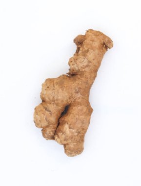 Topraksı, işlenmemiş zencefil kökü, tokmak gibi yapısını ve doğal dokusunu gözler önüne seriyor, organik formunu ön plana çıkaran el değmemiş beyaz bir zemin üzerinde sunuluyor..