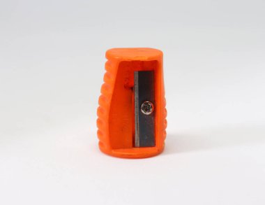 Yakın plan çekimde parlak beyaz bir arkaplan üzerinde dikey konum alan parlak turuncu kalemtraşlı parlak bir bıçak, berraklık ve odaklanma sağlar..