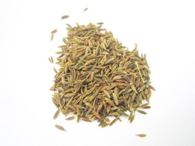 Beyaz bir yüzeye yayılmış kahverengi kimyon tohumları yığını, şeffaf bir arkaplan