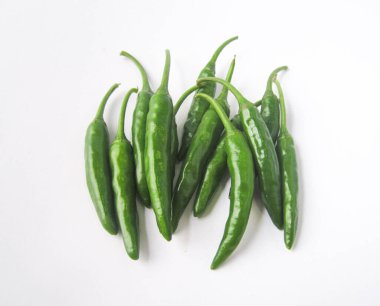 Saf beyaz yüzeyde birkaç taze yeşil biber bir araya toplanır.