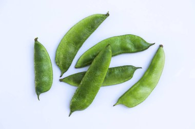 Gıcır gıcır bir stüdyo çekiminde taze yeşil lima fasulyelerinden oluşan bir koleksiyon sergileniyor. Temiz beyaz bir zemin üzerine serilmiş, doğal dokularını ve renklerini ön plana çıkarıyor..