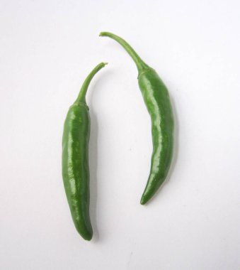 Beyaz yüzeyde iki taze yeşil biber var.