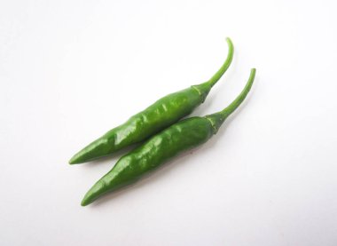 İki canlı yeşil biber, beyaz bir yüzeye yakın bir şekilde uzanır.