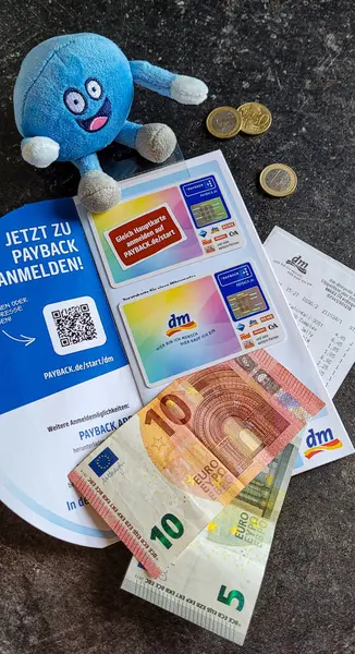 DM, Rewe, Aral, Fressnapf, Penny, C ve A 'dan geri ödeme kartı, Mein Real, para, çek ve siyah arka planda yumuşak mavi bir oyuncak. Para biriktirmeyi. Almanya, Ueberlingen, 27 Nisan 2024