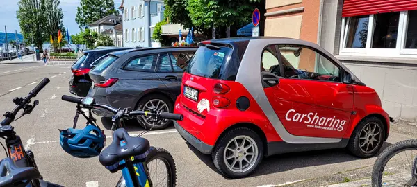 stock image A red car Smart with a logo CarSharing stands of the parkingplace next to other cars and bicycles. Alternative ownership and car use model, a model of car rental. June 08, 2024, Germany, Ueberlingen