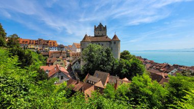 Güzel ortaçağ şatosu Meersburg 'un ve güneşli bir yaz gününde eski kasabanın çatılarının manzarası. Mavi gökyüzünün arka planında Meersburg Şatosu, Constance Gölü ve Alpler.
