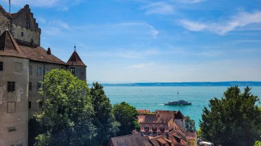 Almanya 'daki güzel ortaçağ şatosu Meersburg manzarası ve güneşli bir yaz gününde eski kasabanın tuğladan çatıları. Meersburg Şatosu mavi gökyüzünün arka planında Alpler, göl Constance cadısı gemi ve yatlar..