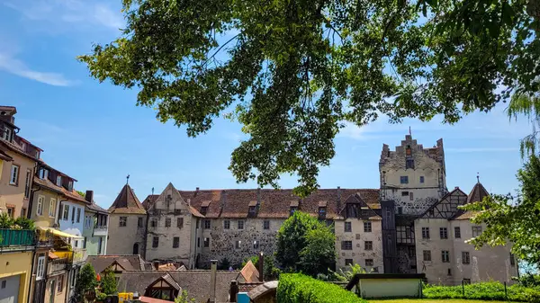 Ortaçağ şatosu Burg Meersburg ve güneşli bir yaz gününde eski kasabanın tuğladan çatıları. Burg Meersburg 'un yeşil ıhlamur ağaçlarını çerçevelemesi, blu' nun arka planına karşı