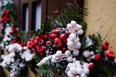 Ahşap pencerelerde Noel süsleri ve süsler var. Karların altında kırmızı çilekler.