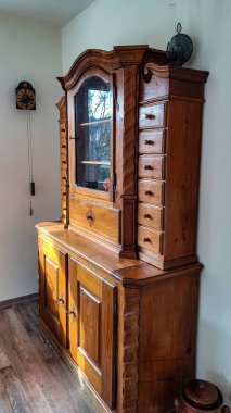 Cam kapıları ve bir sürü çekmecesi olan zarif bir antika ahşap dolap. İç kısımda antika mobilyalar var.