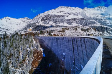 Kops Barajı 'nın beton manzarası. Vorarlberg, Avusturya. Arka planda - karla kaplı Alpler ve mavi gökyüzü