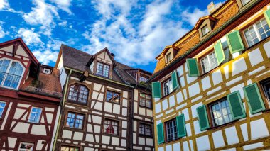 Beautiful and charming medieval timber framing houses on the background of blue sky with white clouds. clipart