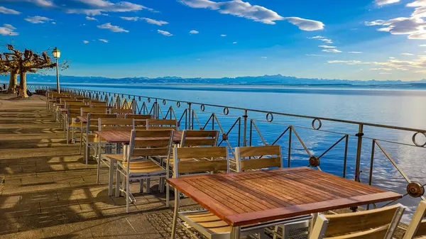 Meersburg 'da, güneşli bir kış gününde İsviçre, Constance Gölü ve Alpler manzaralı bir gezinti. Gölün kıyısındaki sandalyeye boş masalar..