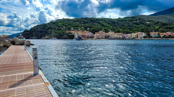 Denizden Akdeniz Riviera Marciana Marina, Elba 'ya manzara. Ön planda, iskele altyapısı ve ahşap yol unsurları var. Arka planda tipik İtalyan evleri var.