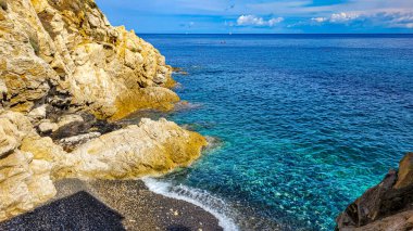 A picturesque view of a beach La Fenicetta with clear azure water. On the back - two yachts and one boat. Horizontal format. Elba, Marciana Marina. clipart