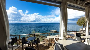 Güneşli bir günde, beyaz perdeli açık pencerelerden açık terastan masmavi denize manzarayı seyret. İtalya, Toskana 'daki Akdeniz kenarı. Pomonte, Elba 'da Tatil.