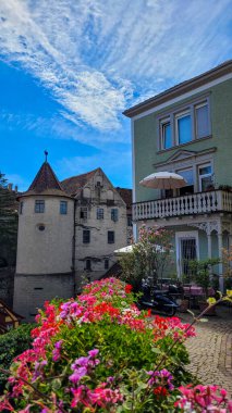 Meersburg Ortaçağ kasabasının pitoresk köşelerinden birine bakıyorum. Ön planda, arkasında pembe ve kırmızı sardunya çiçekleri, Meersburg Şatosu, Burg Meersburg- Almanya.