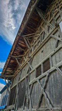 Geleneksel Avusturya ahşap evinin bir parçası açık beyaz bulutlu mavi gökyüzüne karşı. Dikey biçim