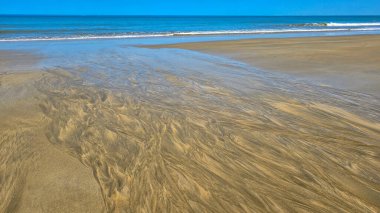 Plaj Plage Des Zeytinleri 'ndeki kum deseni, Soulac sur Mer' deki Fransız Atlantik Kıyısı. Arka planda mavi okyanus ve gökyüzü