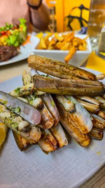 Kızarmış deniz kabuğu, sarımsak ve maydanozlu jilet. Yakınlarda kızarmış patates var. Dikey biçim